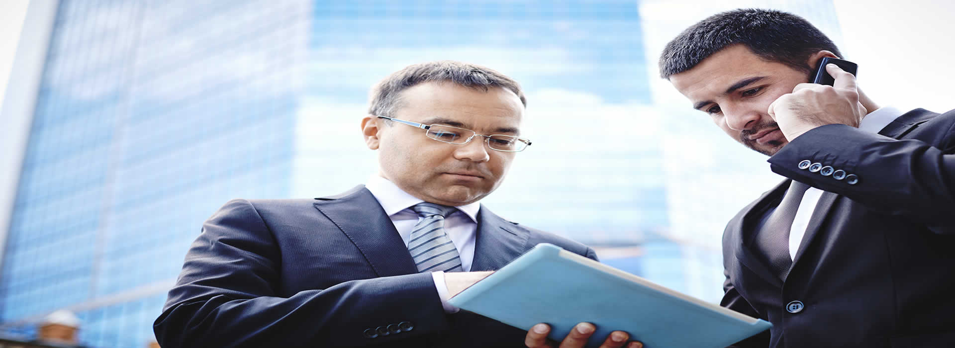 Two businessmen on mobile devices communicating with the office from out in the field
